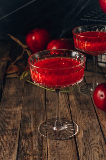 Cocktail di mele rosse con riflessi per la festa di halloween su sfondo rustico in legno