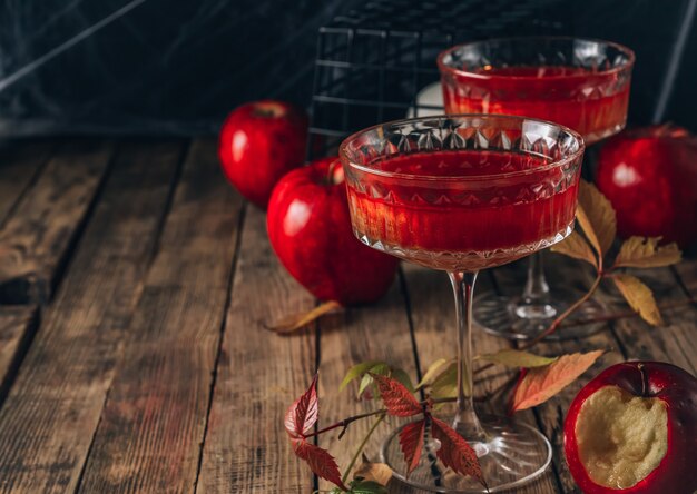 Cocktail di mele rosse con riflessi per la festa di halloween su sfondo rustico in legno