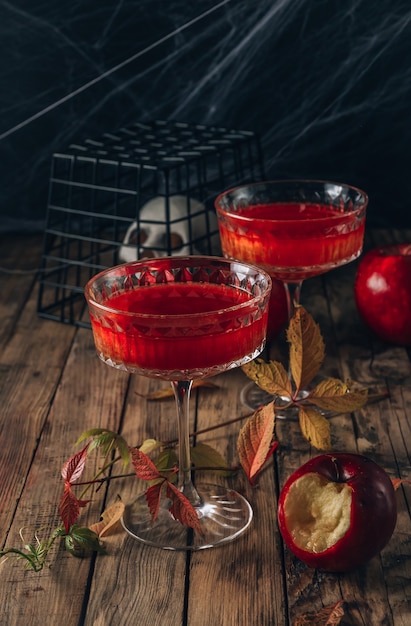 Cocktail di mele rosse con riflessi per la festa di halloween su sfondo rustico in legno