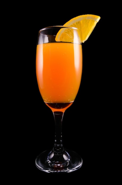 Cocktail di mimosa con una fetta di arancia su un primo piano nero del fondo