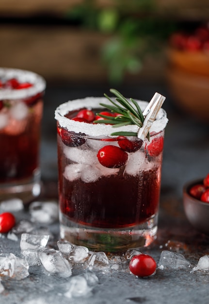 Cocktail di mirtilli rossi con ghiaccio. Bevanda di mirtillo rosso di Natale in bicchieri decorati con zucchero e rosmarino