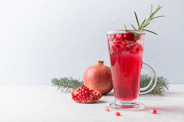 Cocktail di Natale al melograno con spumante guarnito con rametto di rosmarino