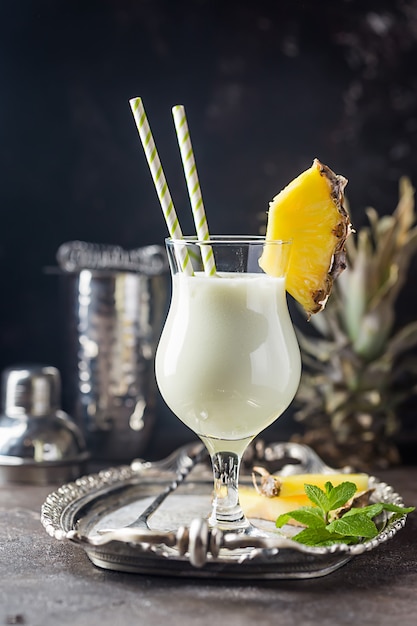 Cocktail di Pina Colada congelato fatto in casa con rum, latte di cocco e ananas guarnito su superficie nera