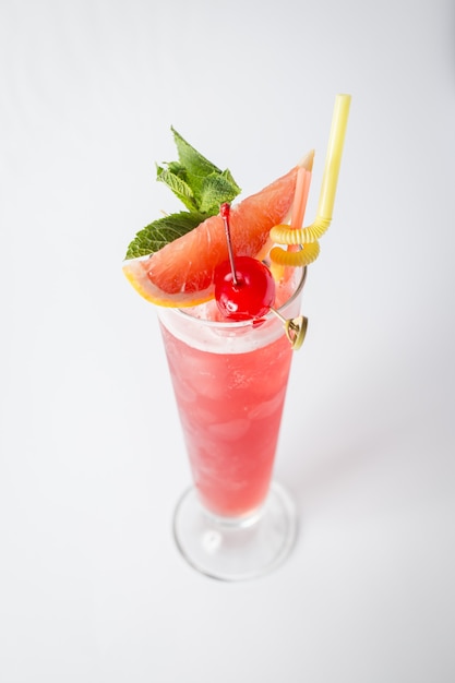 Cocktail di pompelmo fresco alcol con ciliegia e menta su priorità bassa bianca.