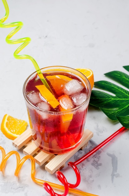 Cocktail di sangria rosso freddo con arancia e ghiaccio in vetro