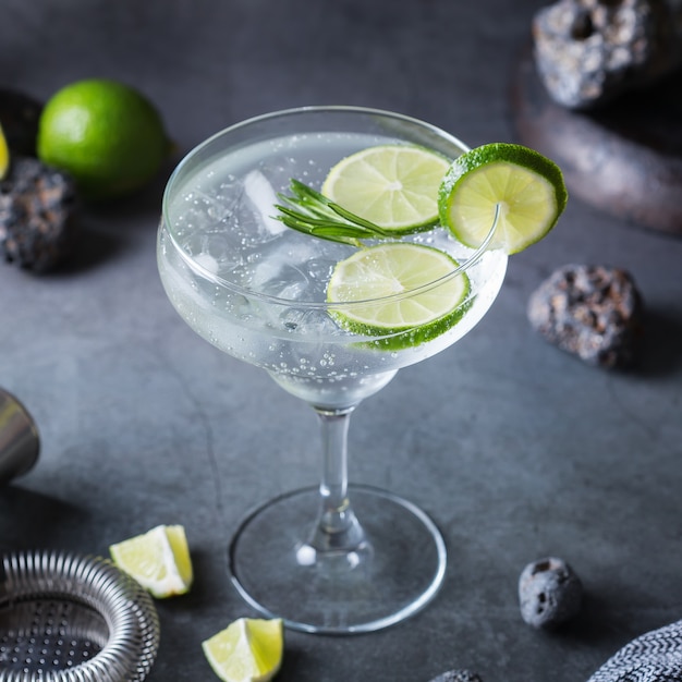 Cocktail di seltz duro con lime, rosmarino e ghiaccio su un tavolo. Bevanda rinfrescante estiva, bevanda