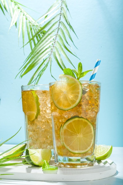 Cocktail di tè freddo Cuba Libre long island con bevanda alcolica forte cola lime e ghiaccio in due bicchieri di cocktail longdrink freddo su sfondo piastrellato azzurro