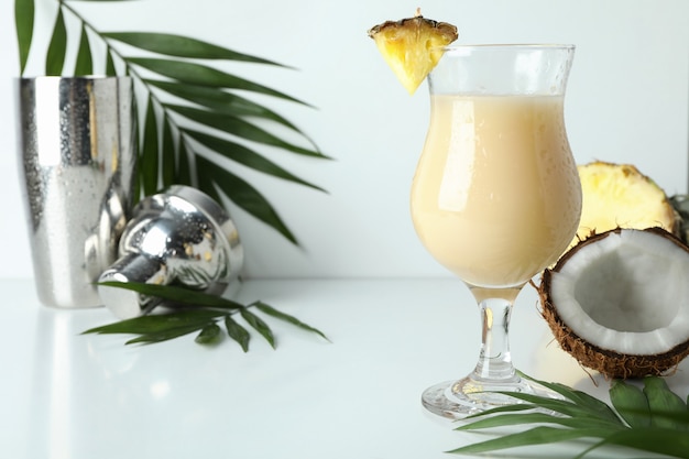 Cocktail e ingredienti di pina colada sulla tavola bianca.