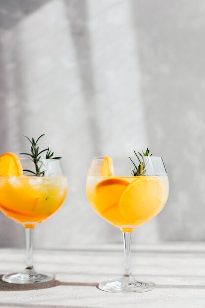 Cocktail estivi rinfrescanti con ramoscello d'arancia e rosmarino su sfondo grigio bevande analcoliche fredde