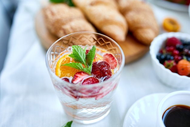 Cocktail estivo con fragole, arancia e menta in vetro sul tavolo bianco