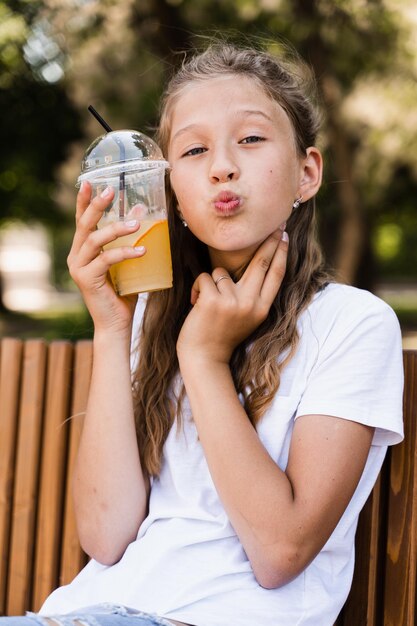 Cocktail estivo di limonata all'aperto Ragazza felice che tiene tazza con limonata arancione e sorridente e ridente