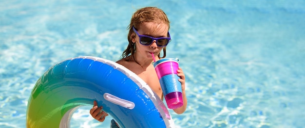 Cocktail estivo per bambini Ragazzino felice con anello gonfiabile colorato nella piscina all'aperto in una calda giornata estiva Vacanza al mare in famiglia Banner per lo spazio della copia dell'intestazione Poster per il web design