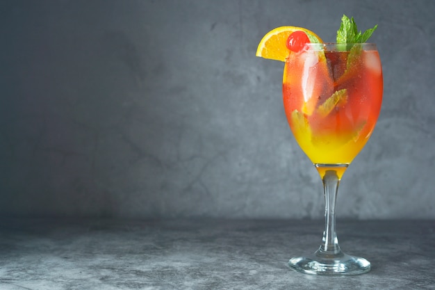Cocktail estivo. Succo d'arancia con menta, soia, fette di frutta e ciliegia con ghiaccio.