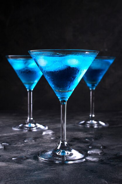 Cocktail freddo blu nel bicchiere da martini con ghiaccio e gocce di rugiada chiare