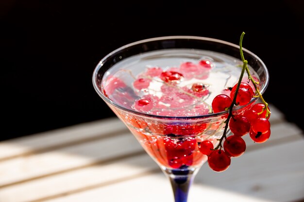 cocktail freddo estivo. Bacche fresche cadute in acqua Ribes rosso succoso con gocce d&#39;acqua