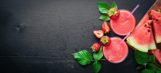 Cocktail fresco di anguria e fragole Ghiaccio alla menta su una tavola di legno Vista dall'alto Spazio libero per il testo