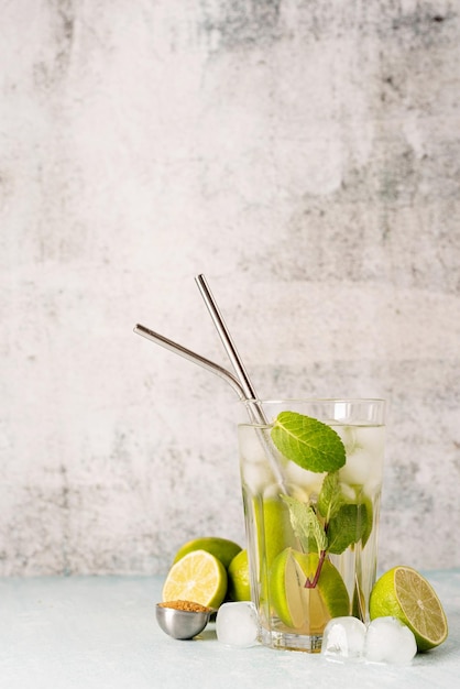 Cocktail fresco di caipirinha estivo su fondo di cemento con lime di frutta verde sul tavolo