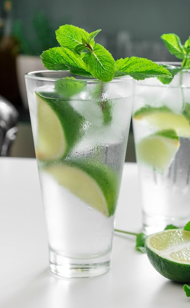 Cocktail Gin Tonic o Mojito in vetro con menta, ghiaccio, lime su fondo bianco.