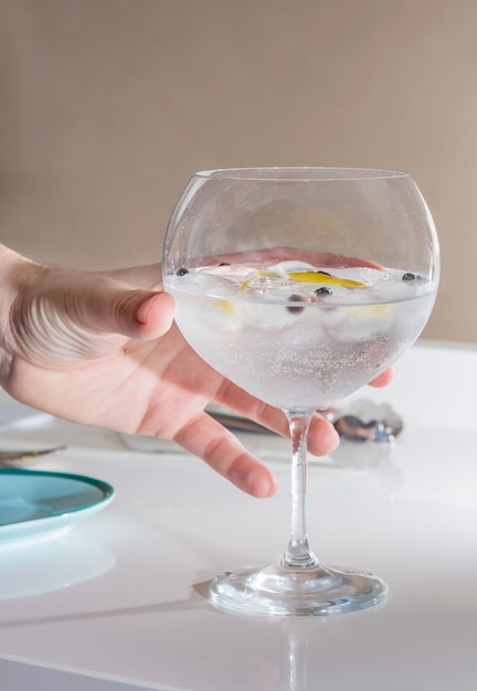 Cocktail gin tonic raccolto a mano servito su un bicchiere