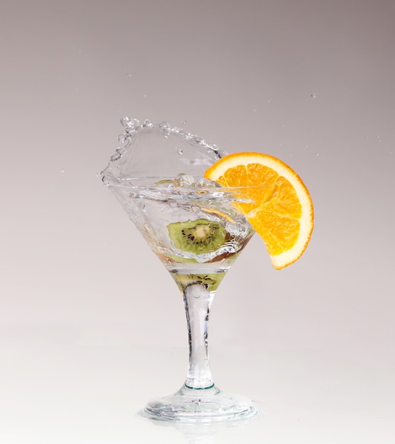 Cocktail in un bicchiere da martini su bianco con frutta