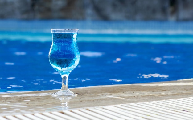 cocktail laguna blu contro il mare o l'acqua della piscina che scorre dal vetro. anello gonfiabile forma unicorno