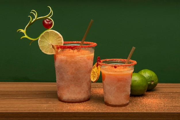 Cocktail margarita messicano con sale al frutto della passione congelato e peperoncino con lime e paglia in un bicchiere di plastica