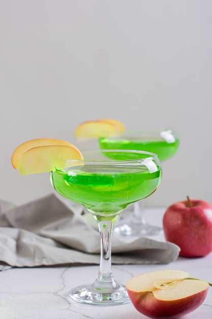 Cocktail martini alla mela verde fatto in casa con pezzi di mela in bicchieri vista verticale