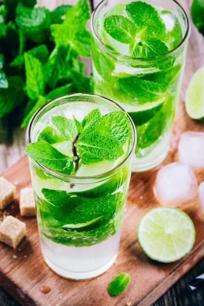 Cocktail mojito freschi con menta lime e ghiaccio in vetro su fondo di legno