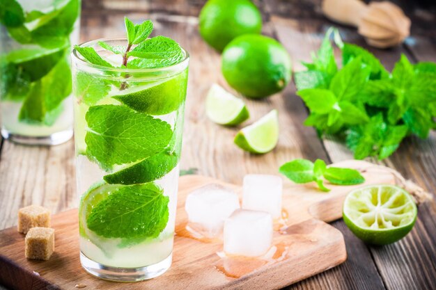 Cocktail mojito freschi con menta lime e ghiaccio in vetro su fondo di legno