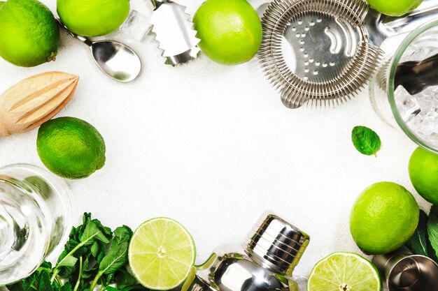 Cocktail Mojito preparazione ingredienti lime menta ghiaccio e strumenti bar sfondo bianco vista dall'alto