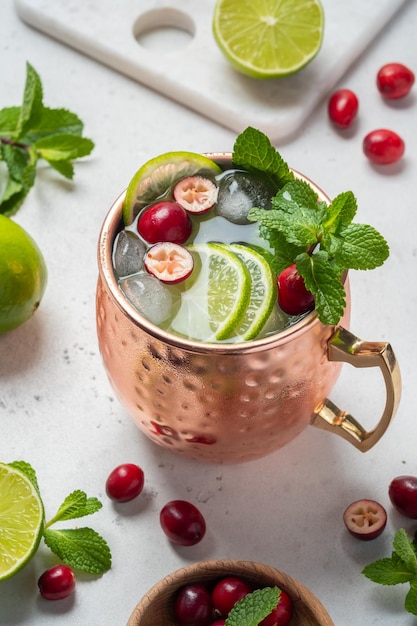 Cocktail Moscow Mule con mirtilli rossi e lime in tazze di rame per Natale