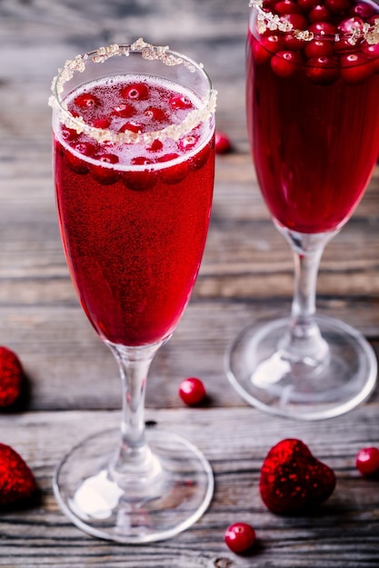 Cocktail rinfrescante con spumante e mirtillo rosso per San Valentino su fondo di legno