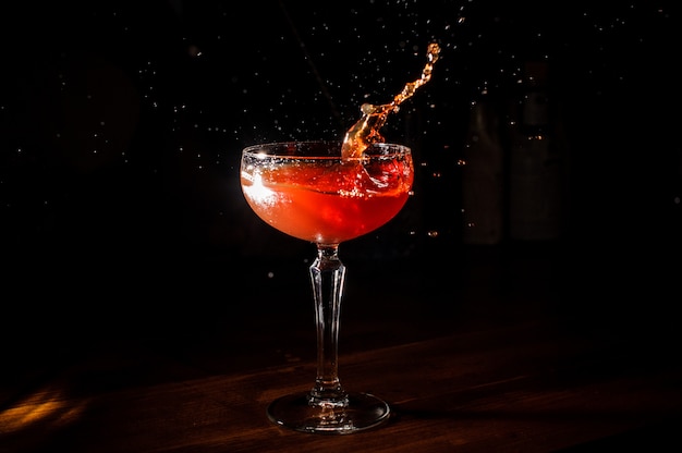 Cocktail rosso che spruzza nel bicchiere