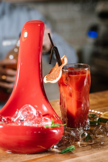 Cocktail rosso chiamato Blood Mary con ghiaccio in vetro sulla tavola di legno