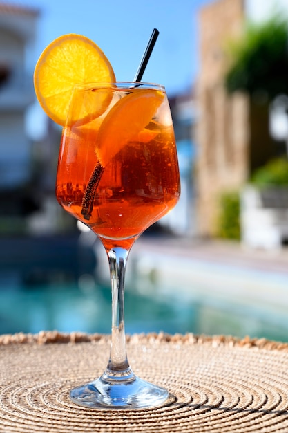 Cocktail rosso con fetta d'arancia e ghiaccio vicino alla piscina di un hotel