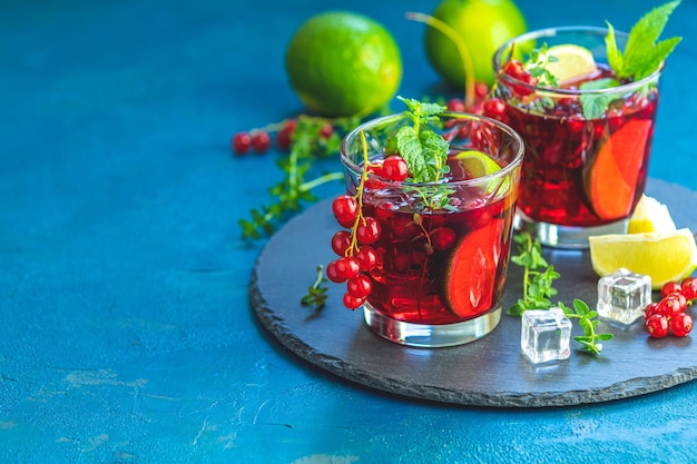 Cocktail rosso freddo con mirtillo, menta, timo e ghiaccio in bicchiere su un tavolo di cemento scuro Bevande estive e cocktail alcolici Mojito di mirtillo