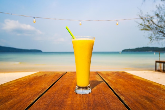 Cocktail sul fondo del mare della tavola Concetto di piacere estivo delle vacanze di vacanza Delizioso frullato di frutta sullo sfondo di una spiaggia deserta su un'isola tropicale in Asia