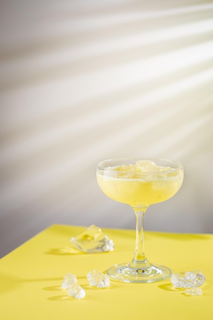 Cocktail tropicale di cocco e banana fresca in un bicchiere su sfondo giallo