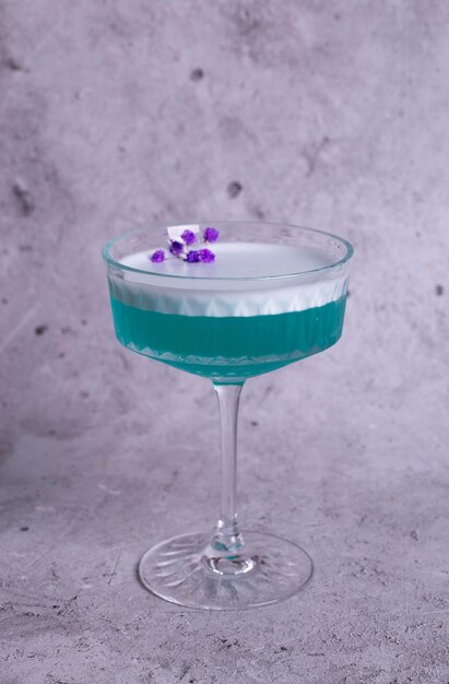 cocktail turchese con un fiore su uno sfondo grigio