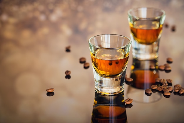 Cognac o liquore, chicchi di caffè e spezie su un tavolo di vetro