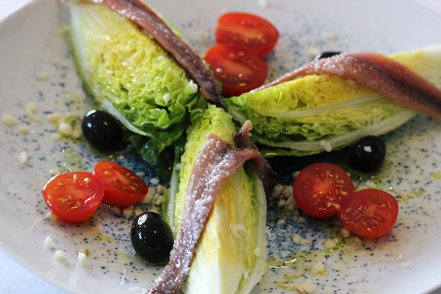 Cogollos de Tudela con acciughe, olive e pomodorini in insalata