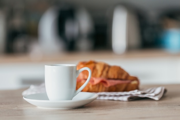 Colazione a base di caffè e panino con cornetto farcito con salame in cucina