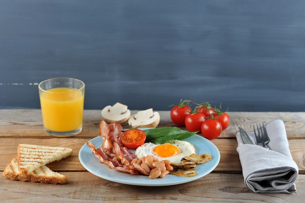 Colazione a base di uova con pancetta, fagioli, funghi, pomodori e spinaci