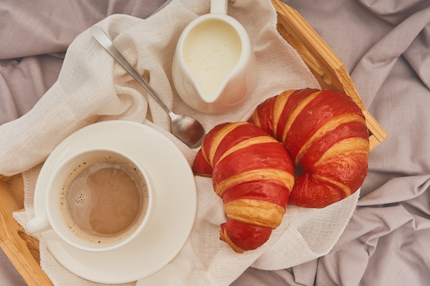 Colazione a letto con caffè espresso, fiori e croissant