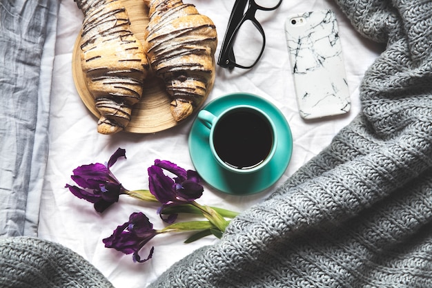 Colazione a letto. Mattina, cornetto, caffè, fiori e un taccuino con una penna. Pianificazione