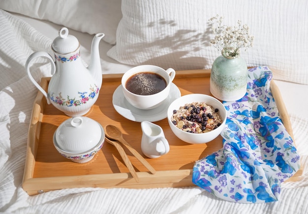 colazione a letto su un vassoio di legno con una tazza di caffè set da tè e farina d'avena