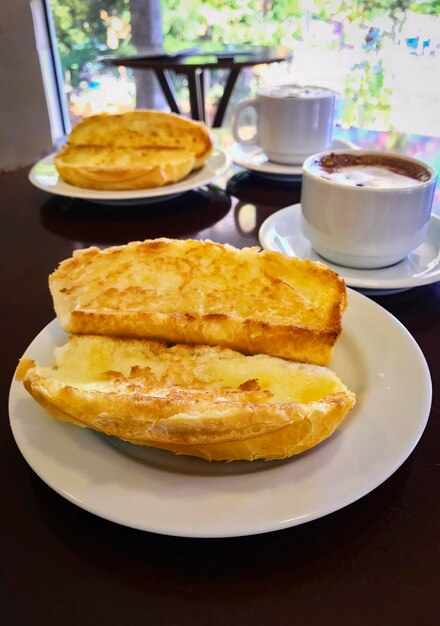 Colazione al Brasile con pane francese tostato con burro sul piatto con cappuccino sul tavolo