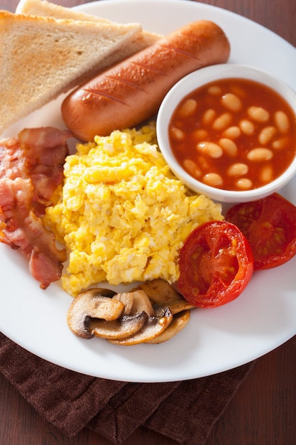 Colazione all'inglese con uova strapazzate, pancetta, salsiccia, fagioli e pomodoro