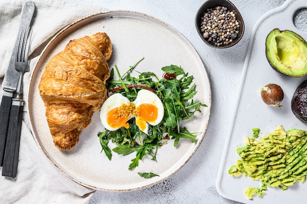 Colazione, brunch con avocado, rucola, croissant e uova