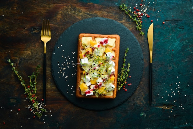 Colazione. Cialde belghe con brie, feta e parmigiano. Su una lastra di pietra nera.